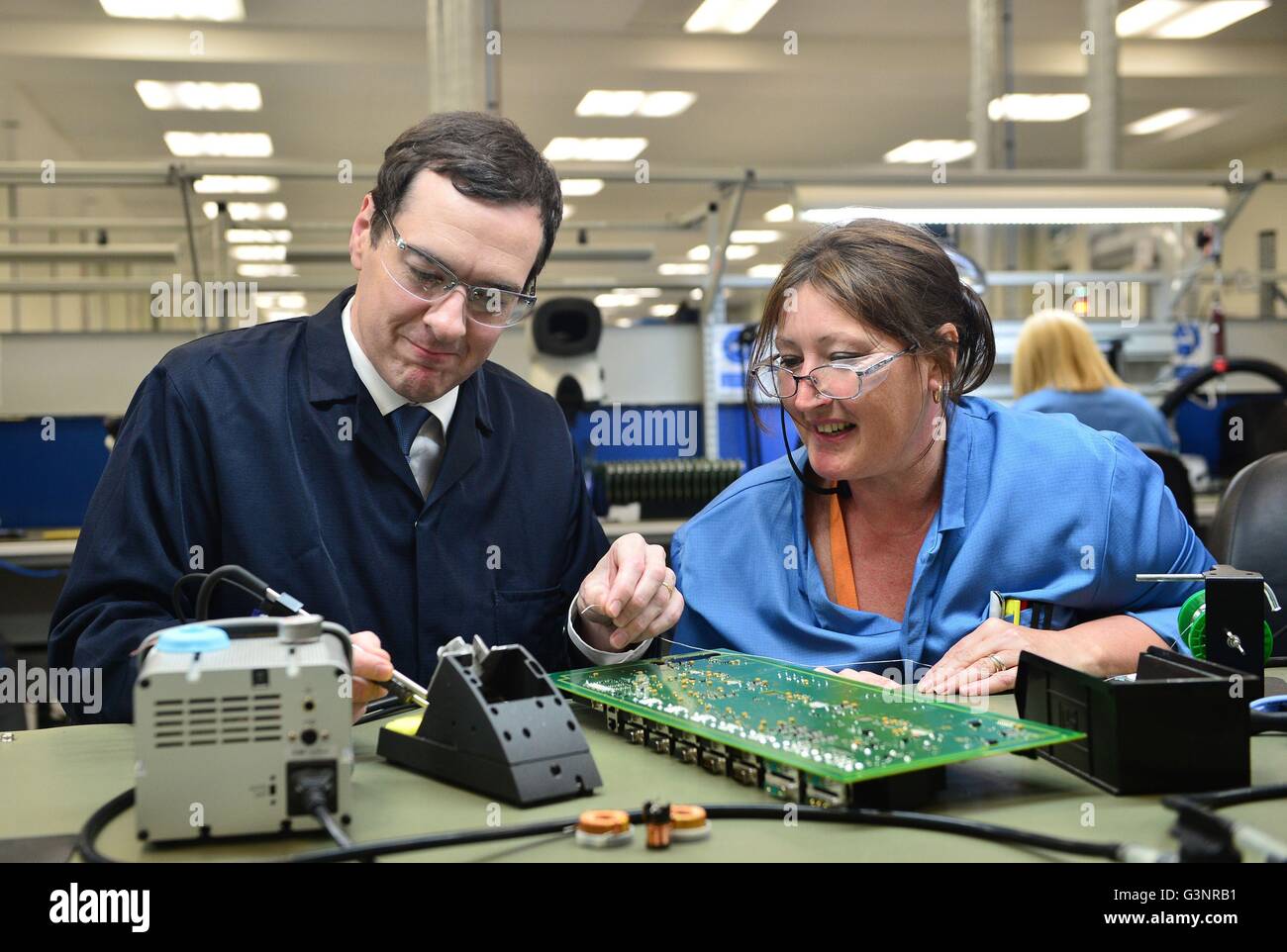 Il cancelliere George Osborne si salda con una scheda a circuito stampato con Karen Greenfield durante un'UE relative visita a Renishaw Plc in Woodchester vicino a Stroud, nel Gloucestershire. Foto Stock