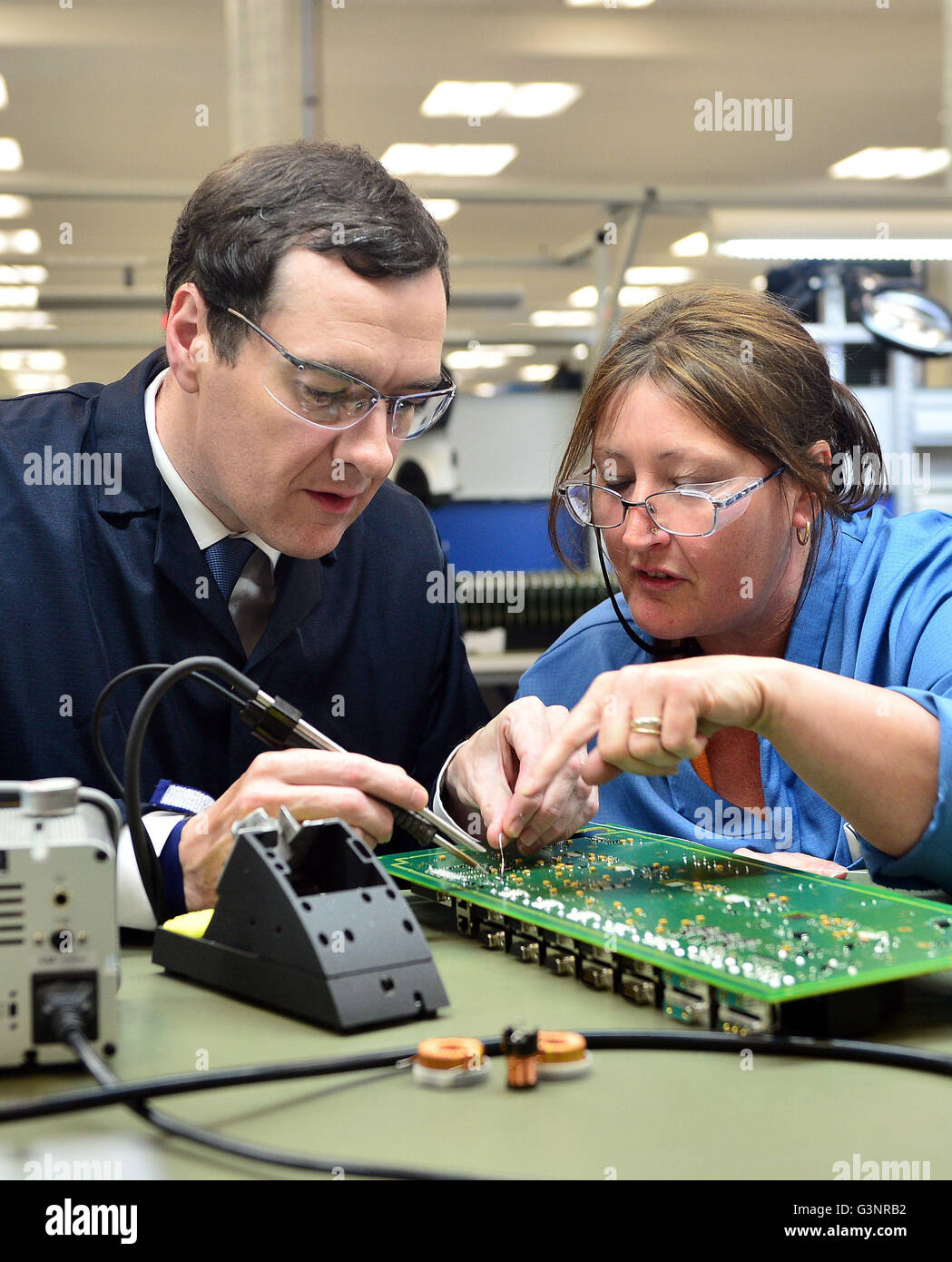 Il cancelliere George Osborne si salda con una scheda a circuito stampato con Karen Greenfield durante un'UE relative visita a Renishaw Plc in Woodchester vicino a Stroud, nel Gloucestershire. Foto Stock