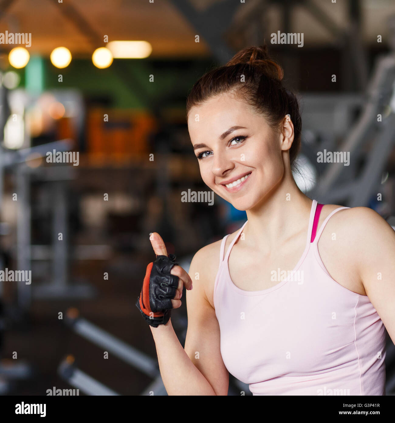Giovane donna sorridente in un centro fitness. Felice bella ragazza in una palestra che mostra pollice in alto Foto Stock