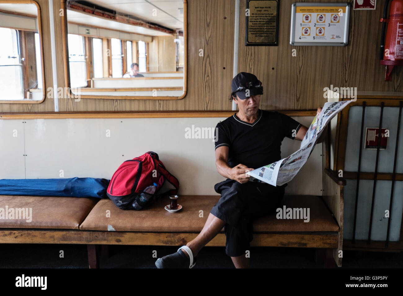 Un " commuter " legge un giornale su un traghetto che viaggia lungo il Bosforo ad Istanbul in Turchia Foto Stock