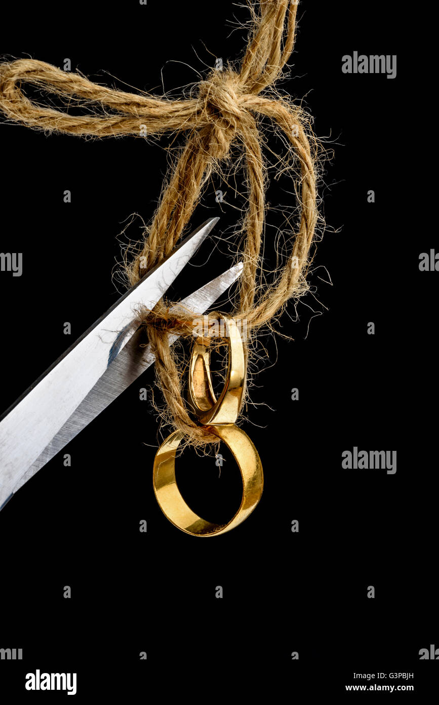 Gli anelli di nozze unite insieme, essendo tagliato mediante forbici. Foto Stock
