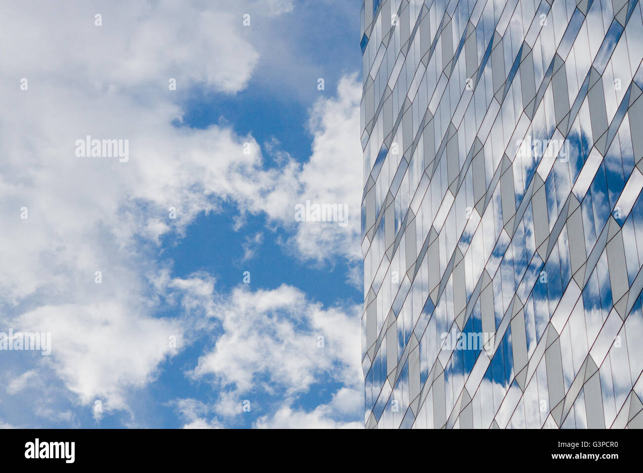Cielo blu e nuvole con la riflessione in un grattacielo in vetro edificio con disegno geometrico Foto Stock