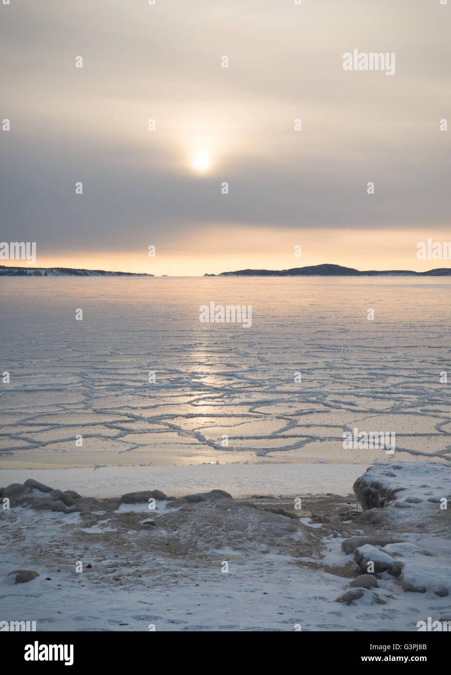 Impostare Bassa sun riflette nel mare di ghiaccio vicino alla riva nell arcipelago esterno Örnsköldsvik nella parte settentrionale della Svezia Foto Stock