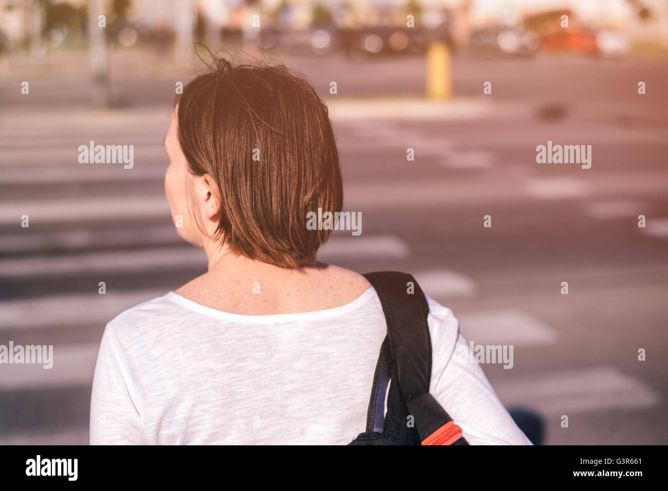 Casual giovane donna adulta camminando sulle strade della città, da dietro, il fuoco selettivo Foto Stock