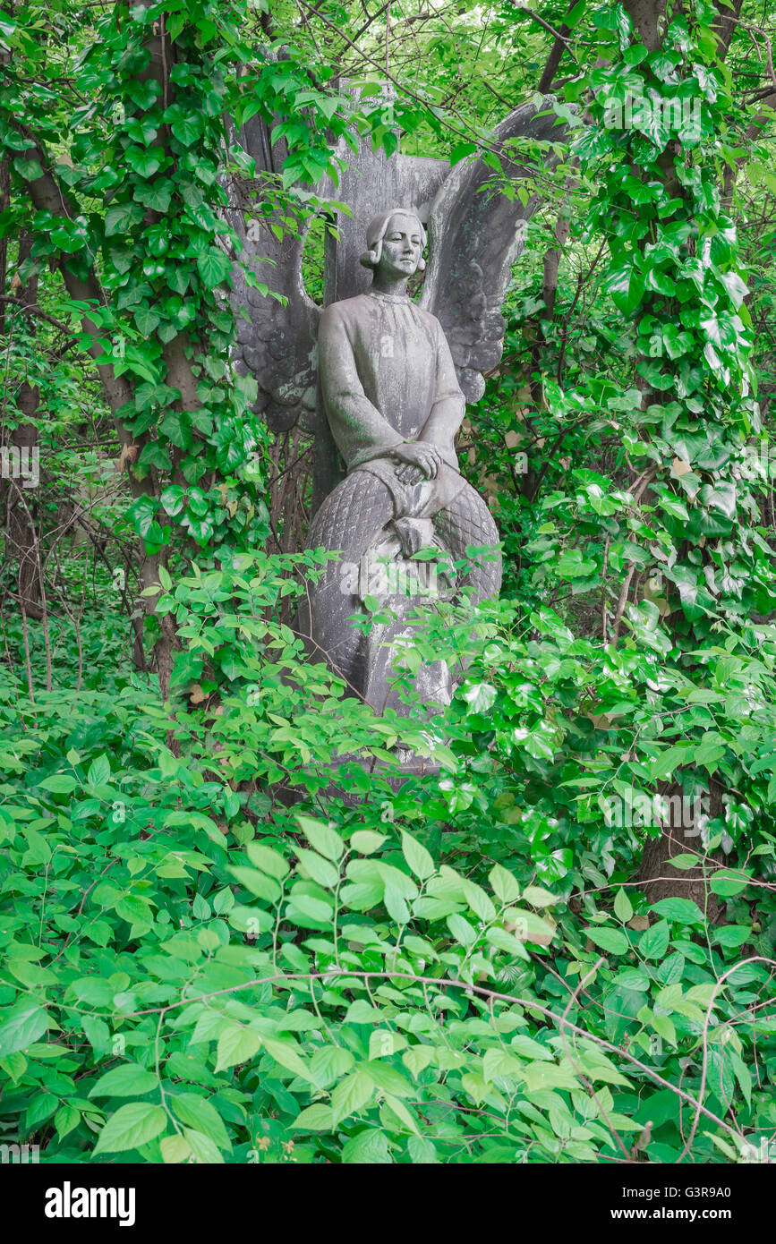 Statua dell'Angelo lapide, vista di una tomba con una lapide d'angelo in pietra, sopravvolta dall'edera nel cimitero di Kerepesi a Budapest, Europa. Foto Stock