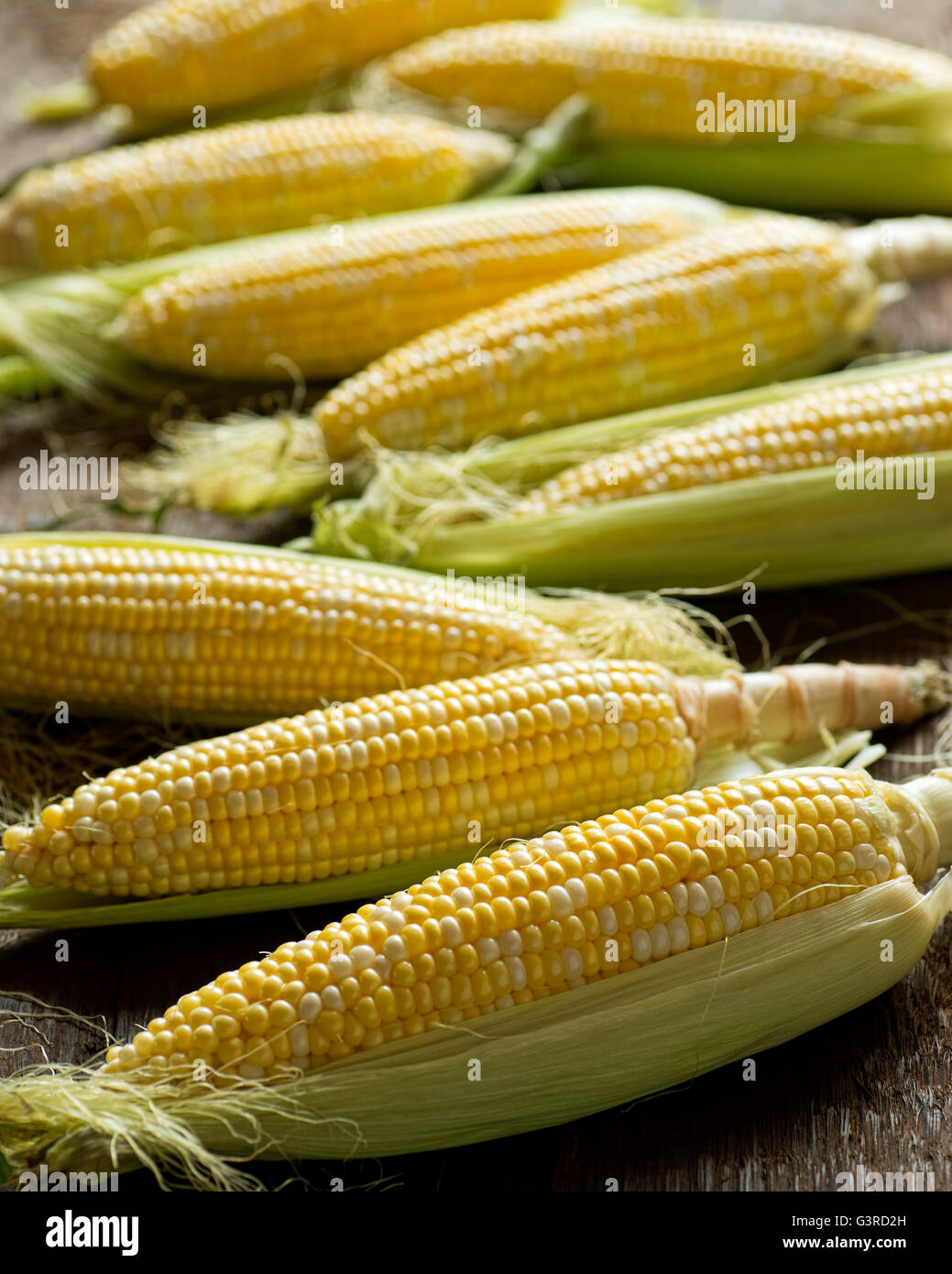 Freschi organici locali sulla pannocchia di mais contro un raccolto rustico sfondo tabella. Foto Stock