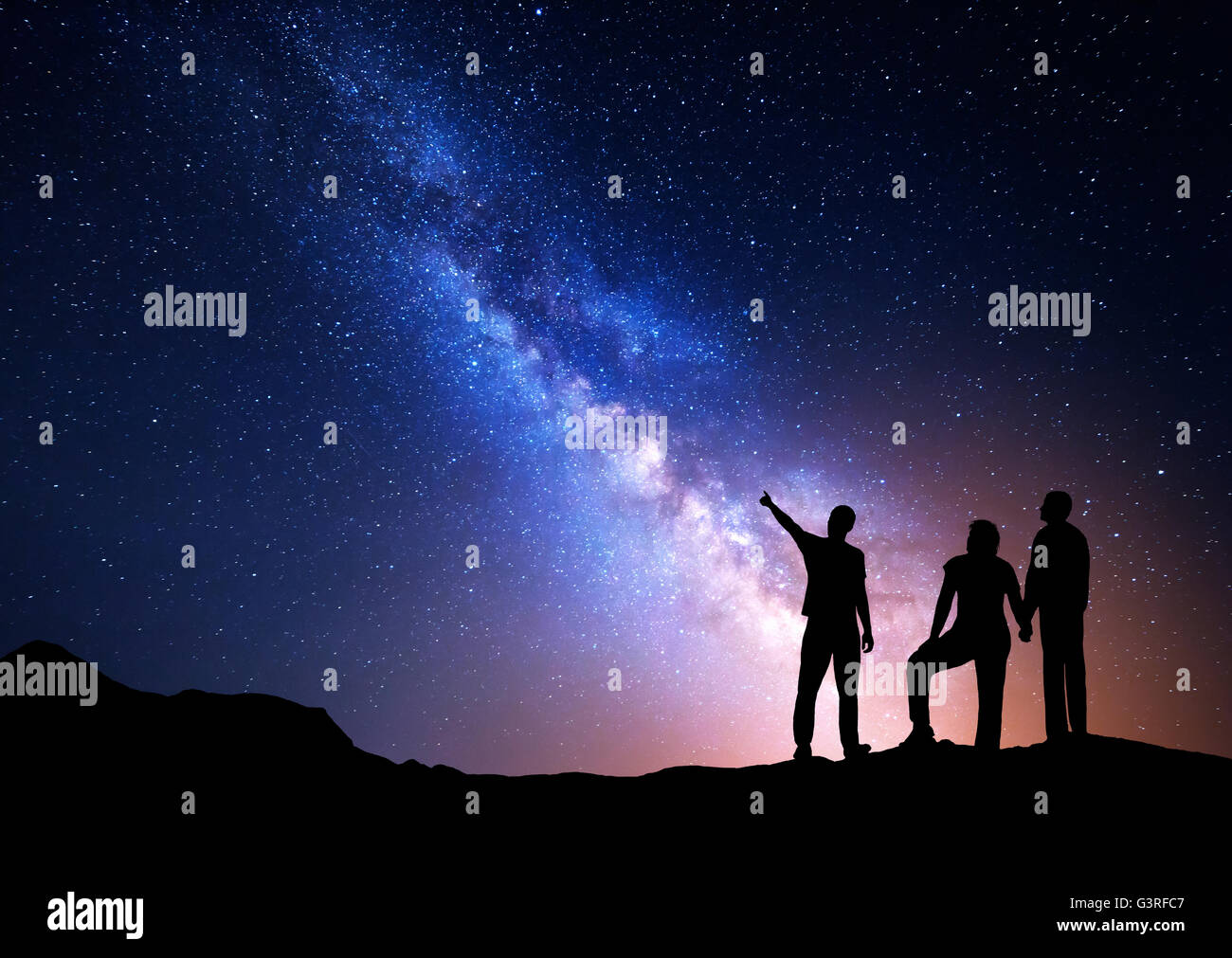 Colorato la Via Lattea con la silhouette di un uomo in piedi puntando il dito nella notte il cielo stellato e i suoi genitori. Silhouette di una famiglia Foto Stock