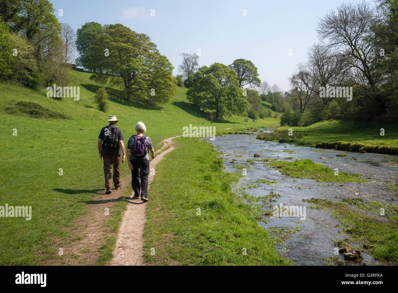 Una coppia matura camminando accanto al fiume in Bradford dale vicino Youlgreave nel Peak District, Derbyshire. Foto Stock