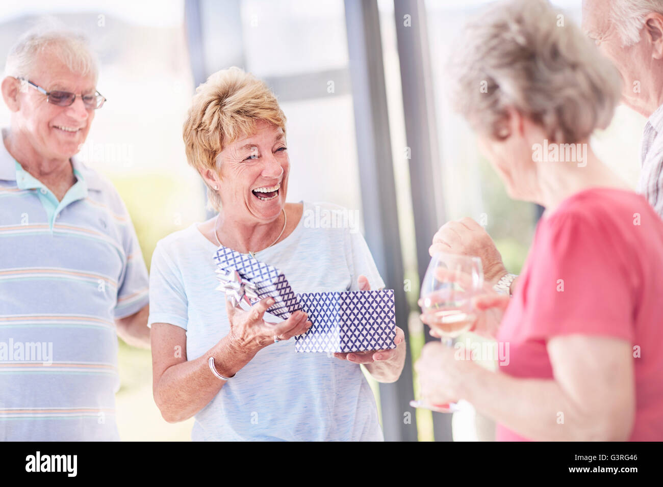 Senior apertura donna regalo di compleanno con gli amici Foto Stock