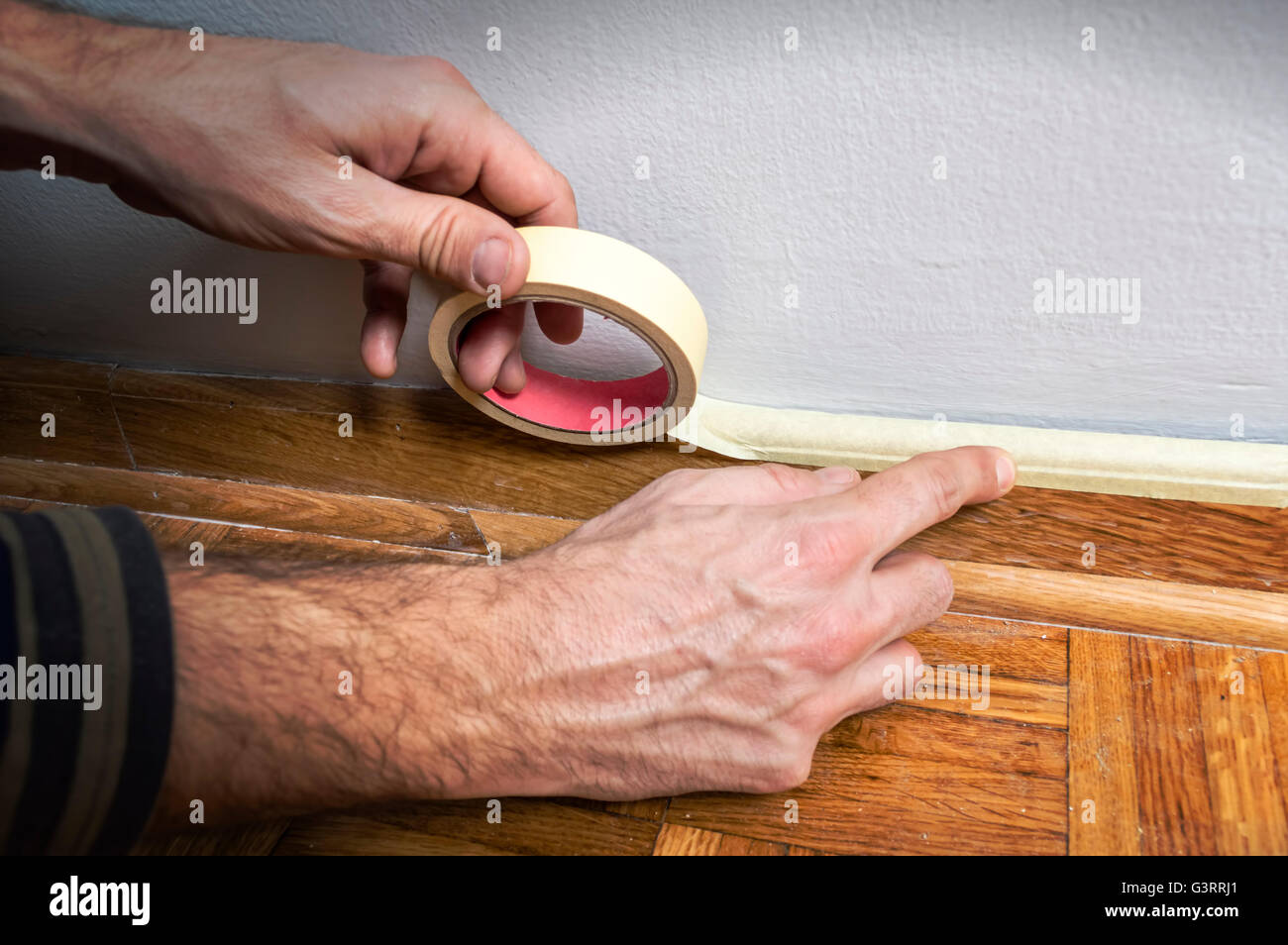 Protezione dei lavoratori batten stampaggio con del nastro adesivo protettivo prima della verniciatura a casa il lavoro di miglioramento. Foto Stock