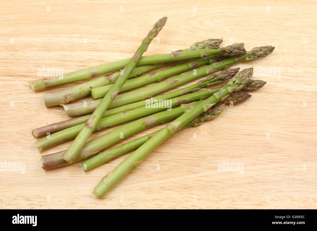 Gli asparagi spears su un tagliere di legno Foto Stock
