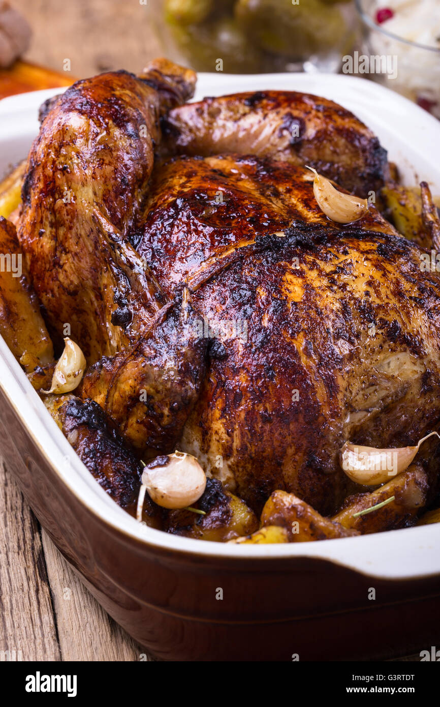 In casa tutto il pollo arrosto con aglio e le patate in una coppa in ceramica Foto Stock