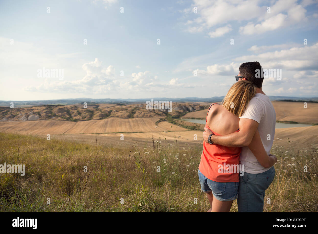 L'Italia, Toscana, abbracciando giovane guardando al paesaggio del campo Foto Stock