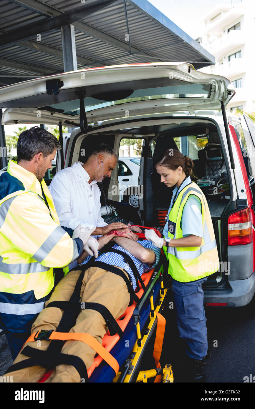 Ambulanza uomini prendersi cura dei feriti sulla barella con medico Foto Stock