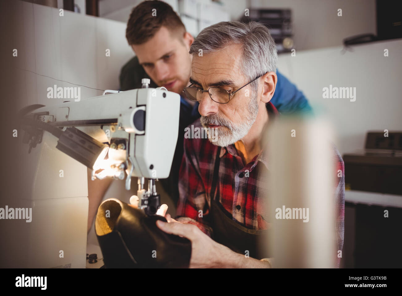 Focus su sfondo di giovani cobbler osservando il lavoro dei suoi vecchi Foto Stock