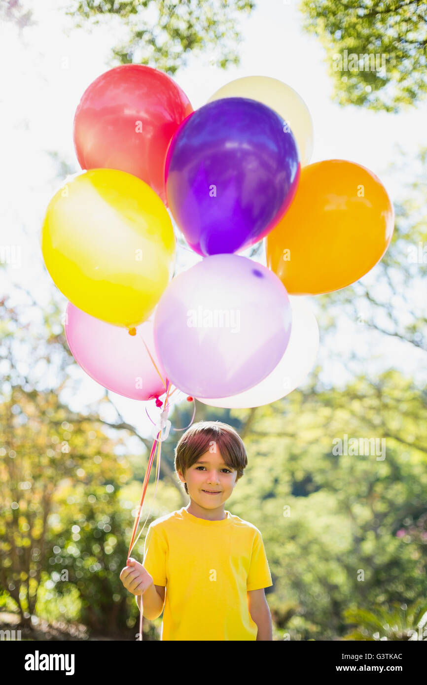 Ritratto di ragazzo sorridente palloncini di trattenimento in posizione di parcheggio Foto Stock