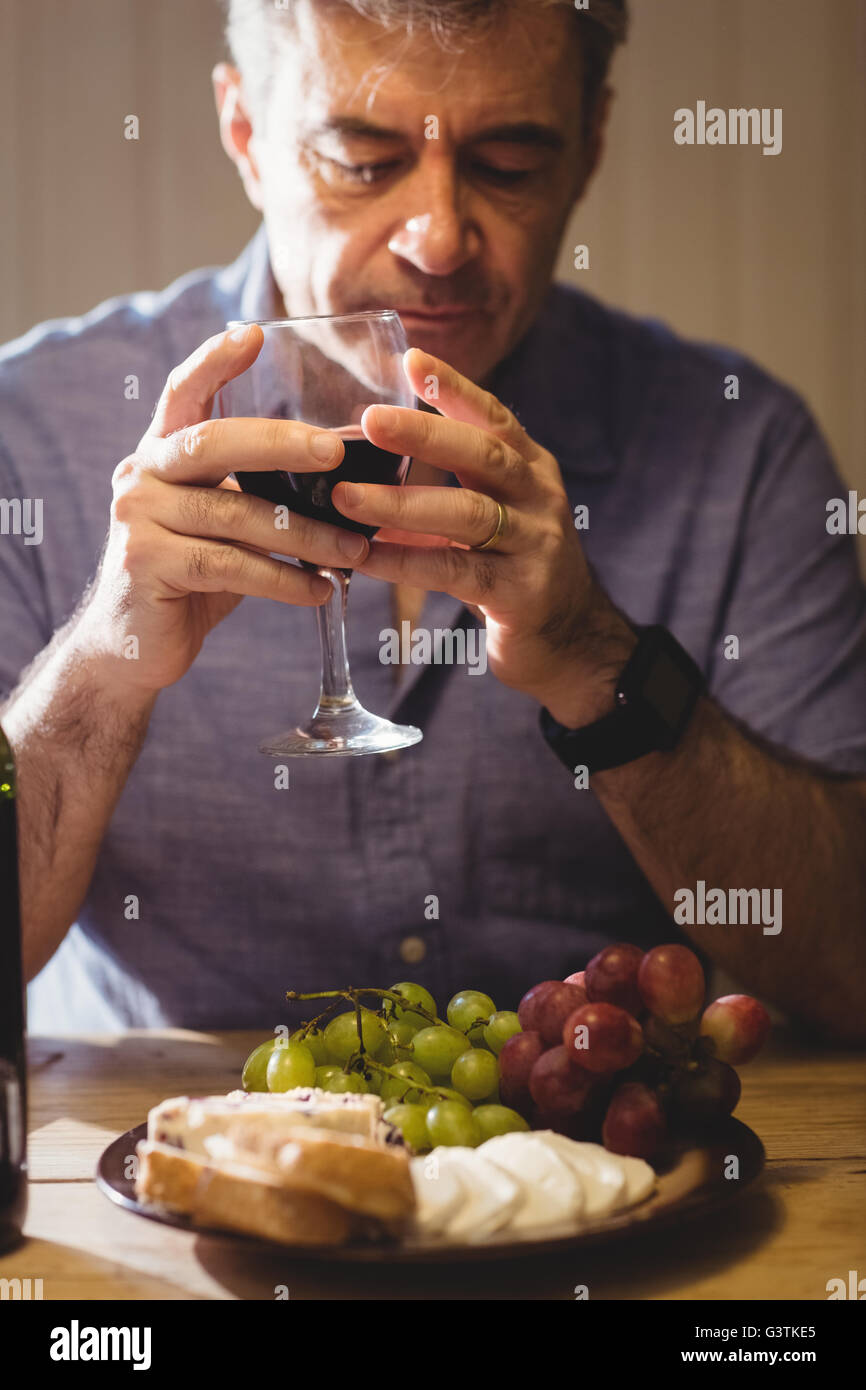 Ritratto di uomo maturo degustazione vino rosso con piastra di formaggi Foto Stock