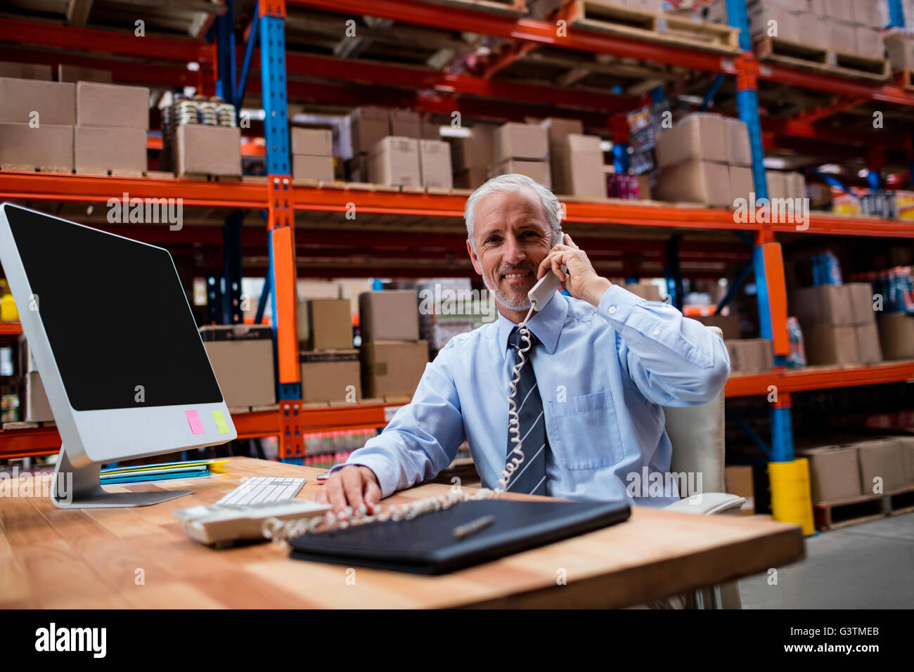 Responsabile di Magazzino utilizzando un laptop parlando al telefono Foto Stock