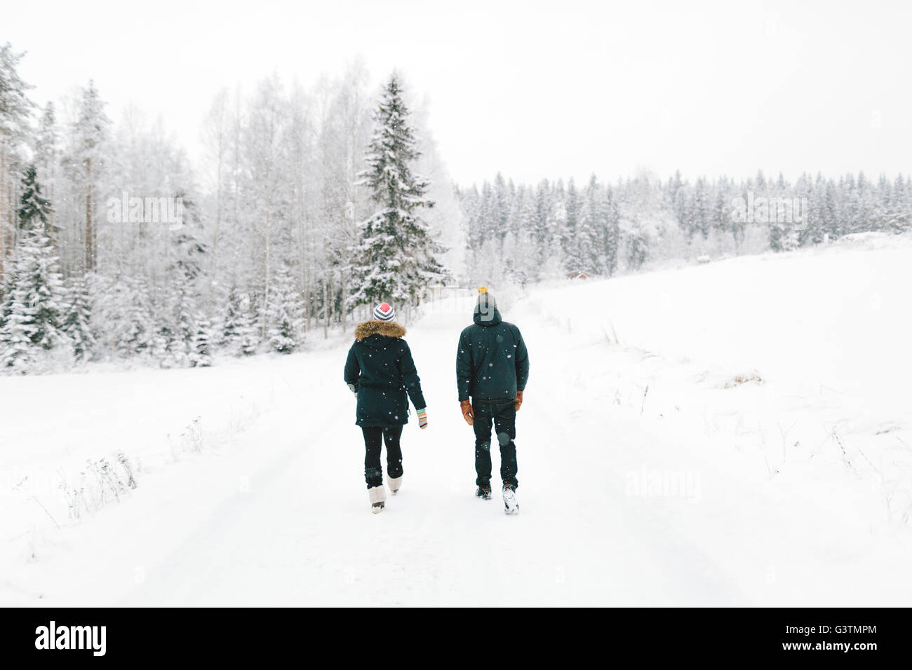 Finlandia, Jyvaskyla, Saakoski, coppia giovane camminando lungo la strada coperta di neve Foto Stock