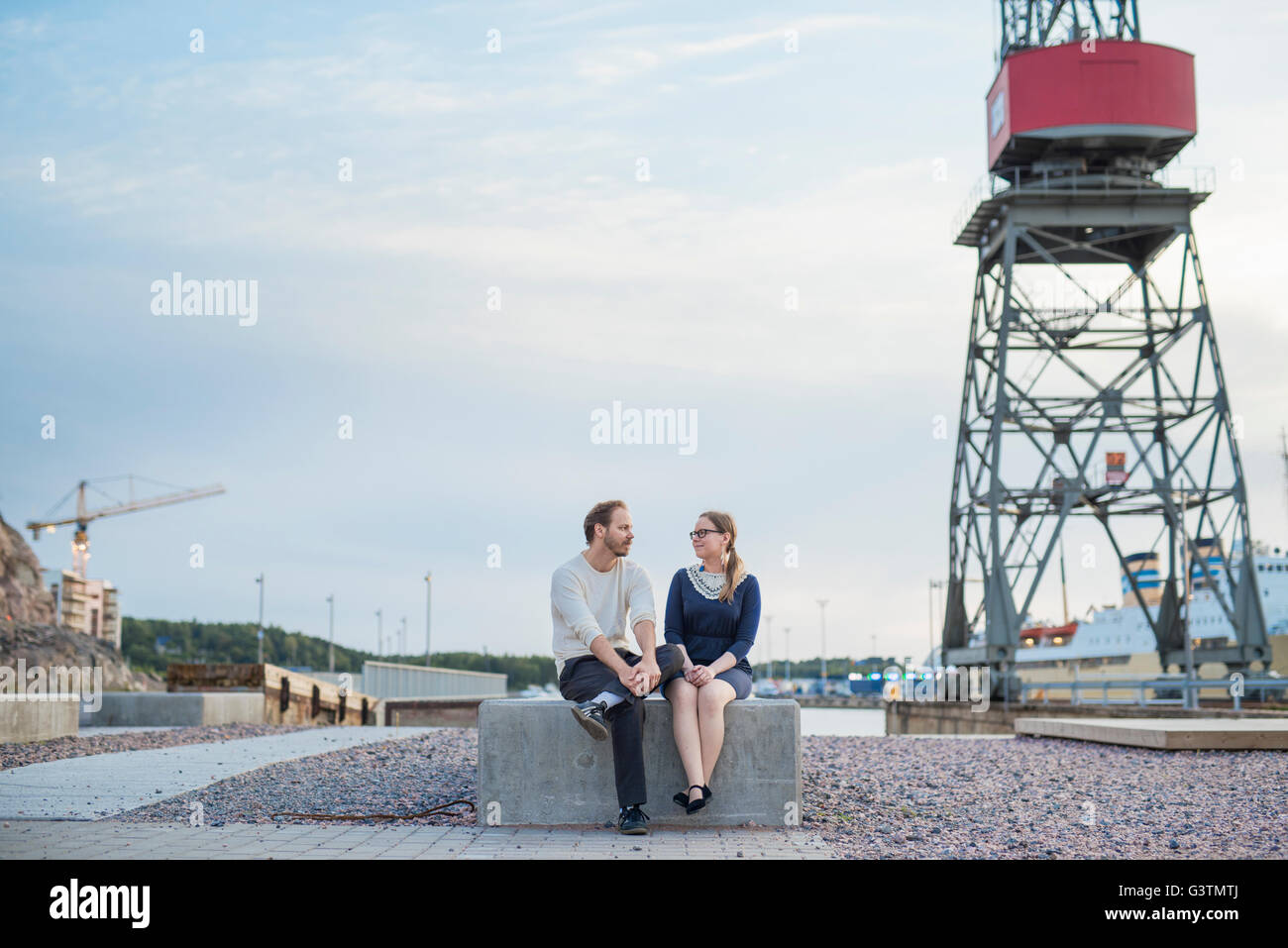 Finlandia, Varsinais-Suomi, Turku, giovane seduto sul blocco e parlando al sito in costruzione Foto Stock