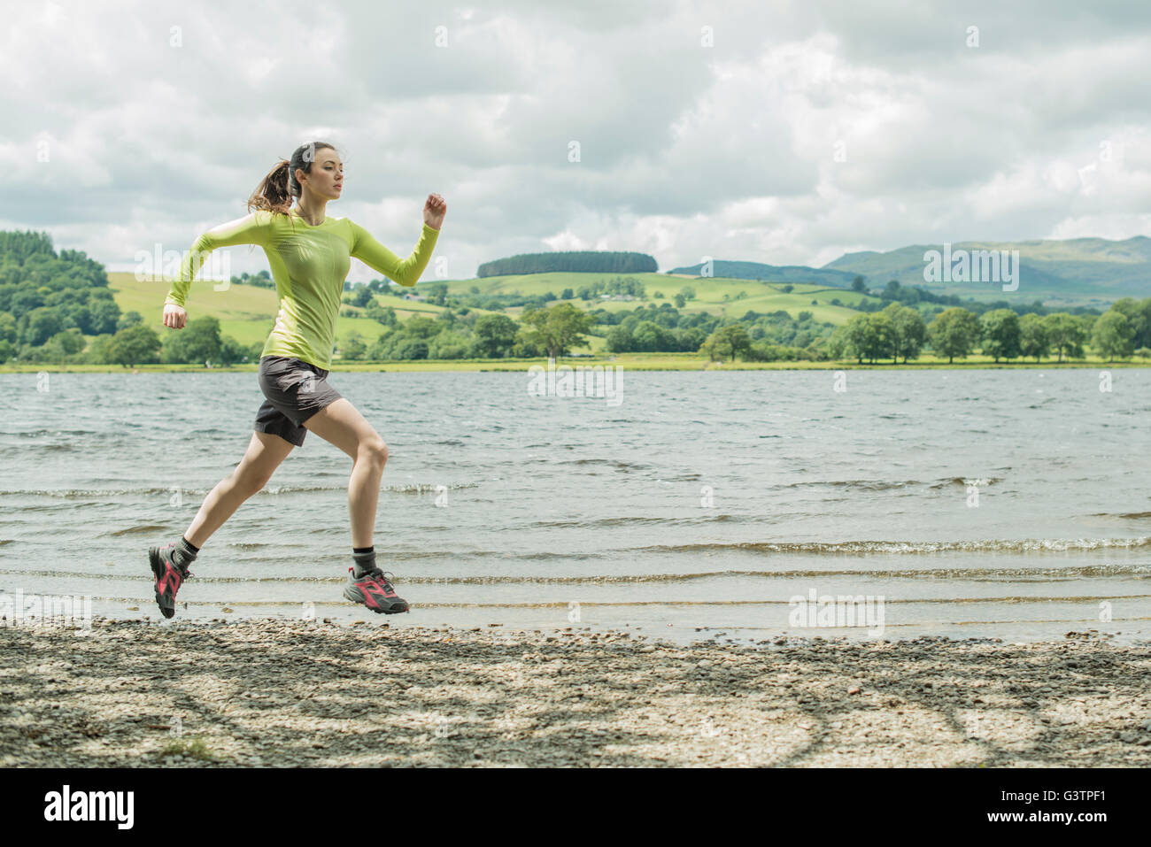 Una ragazza che corre sulla riva accanto a Bala Lake in Galles. Foto Stock
