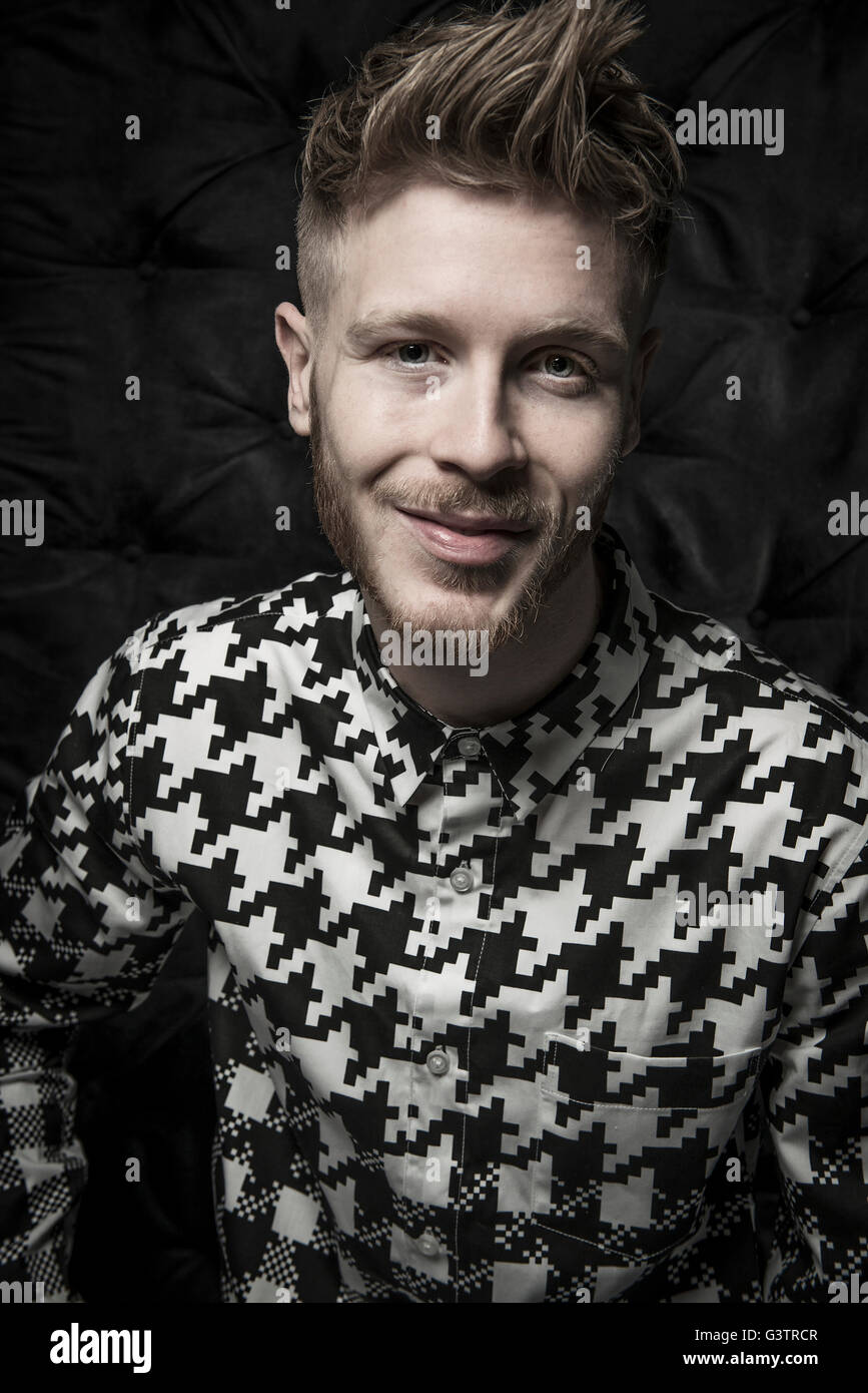 Ritratto in studio di un barbuto giovane uomo in nero e una camicia bianca. Foto Stock