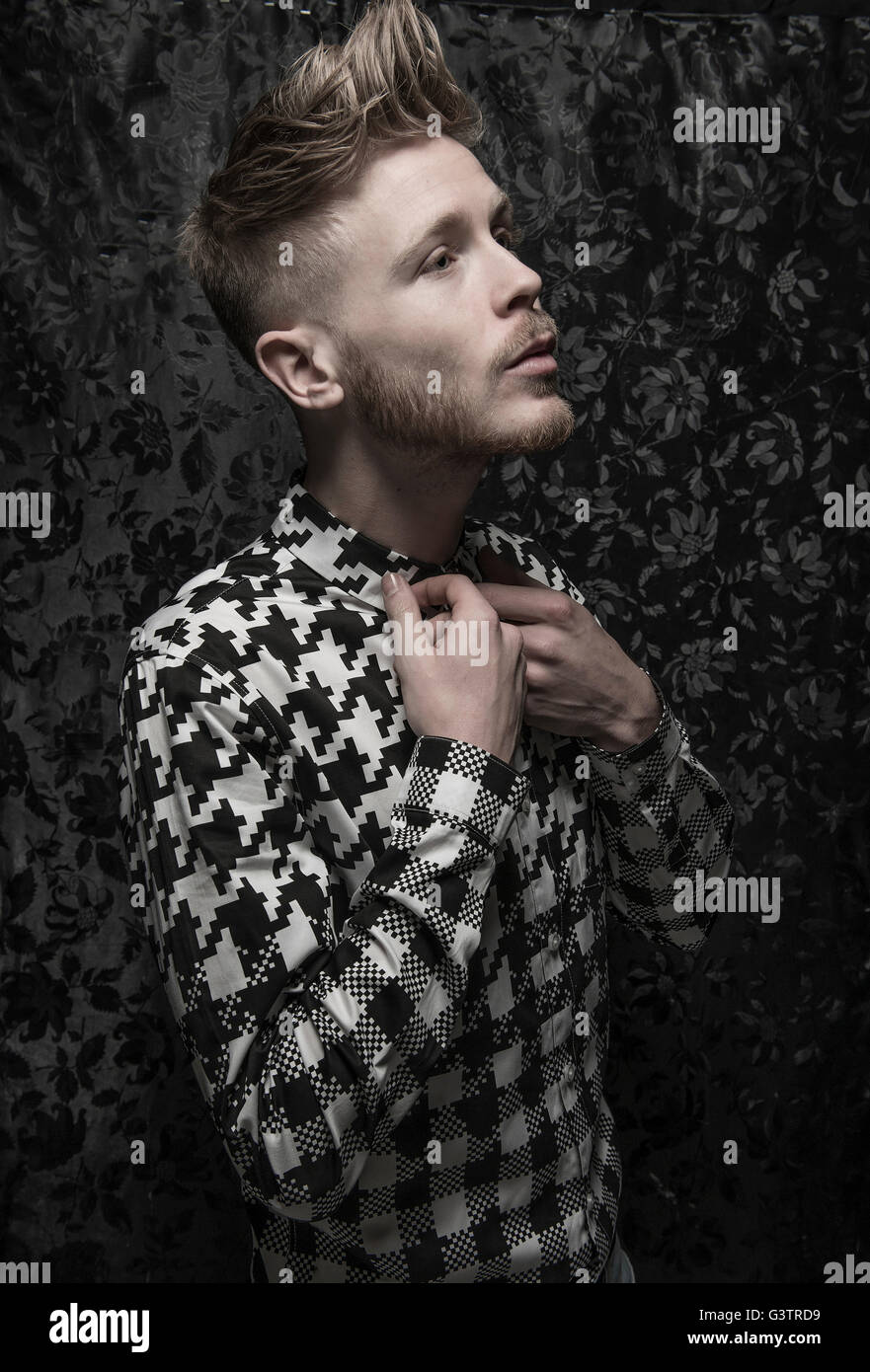 Ritratto in studio di un barbuto giovane uomo in nero e una camicia bianca. Foto Stock