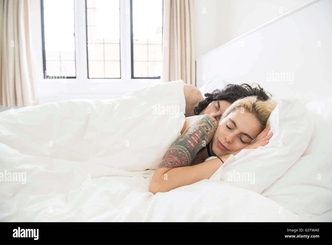 Un giovane tatuato giovane dormono in un letto. Foto Stock