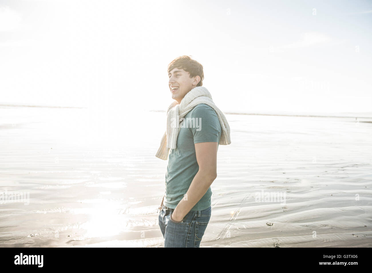 Un giovane uomo godendo il sole sulla spiaggia a Porthmadog. Foto Stock