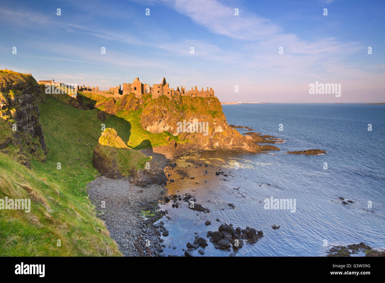 La mattina presto luce solare su Dunluce Castle Al Causeway costa dell'Irlanda del Nord. Foto Stock