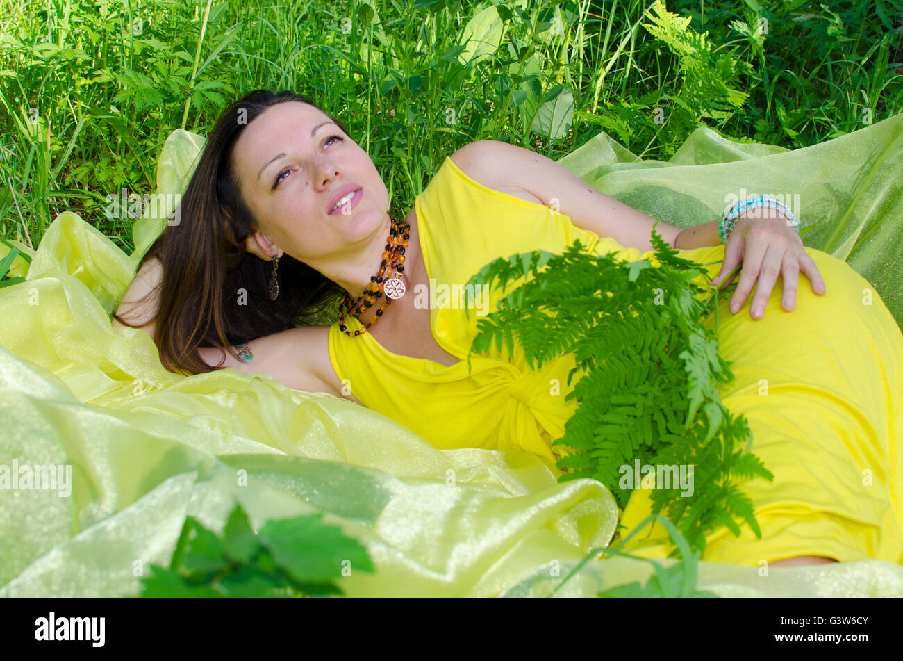 La giovane ragazza dorme sulla questione giallo in natura, giovane, la ragazza dorme, su giallo, materiale verde, un'erba, estate Foto Stock