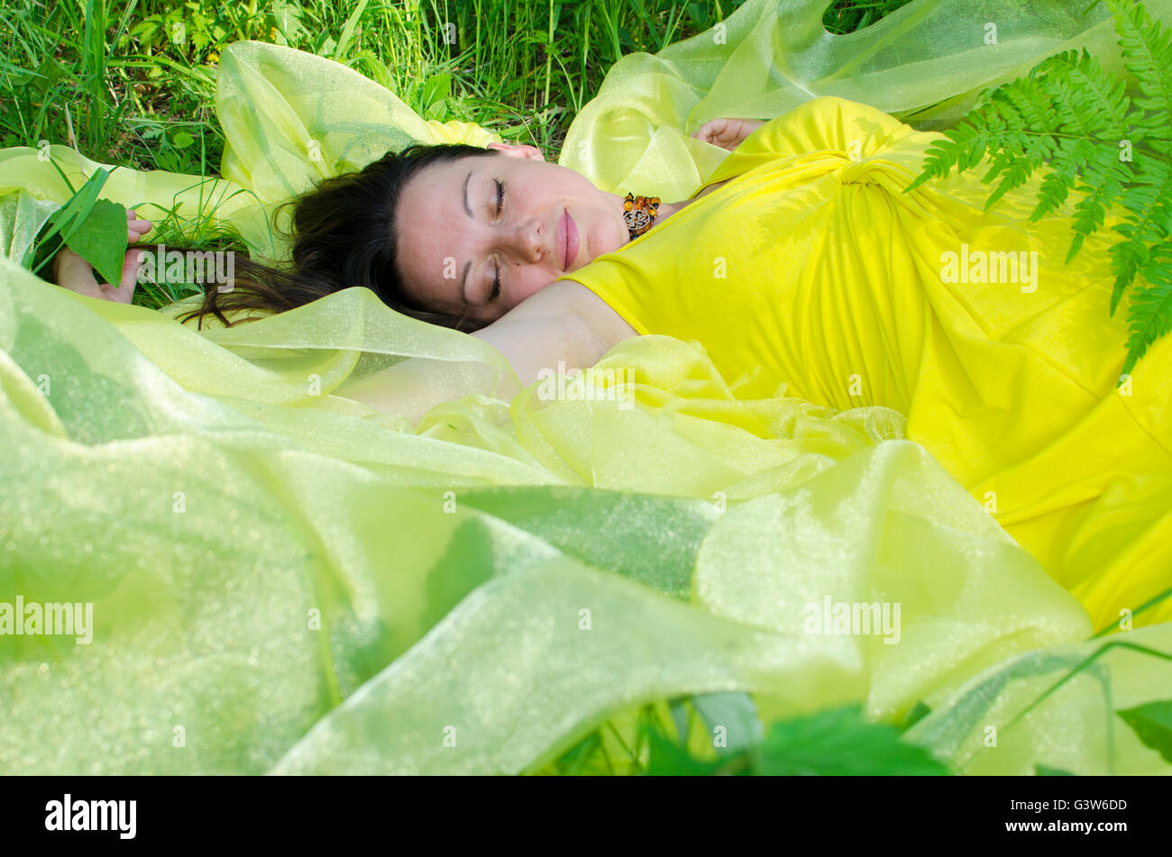 La giovane ragazza dorme sulla questione giallo in natura, giovane, la ragazza dorme, su giallo, materiale verde, un'erba, estate Foto Stock