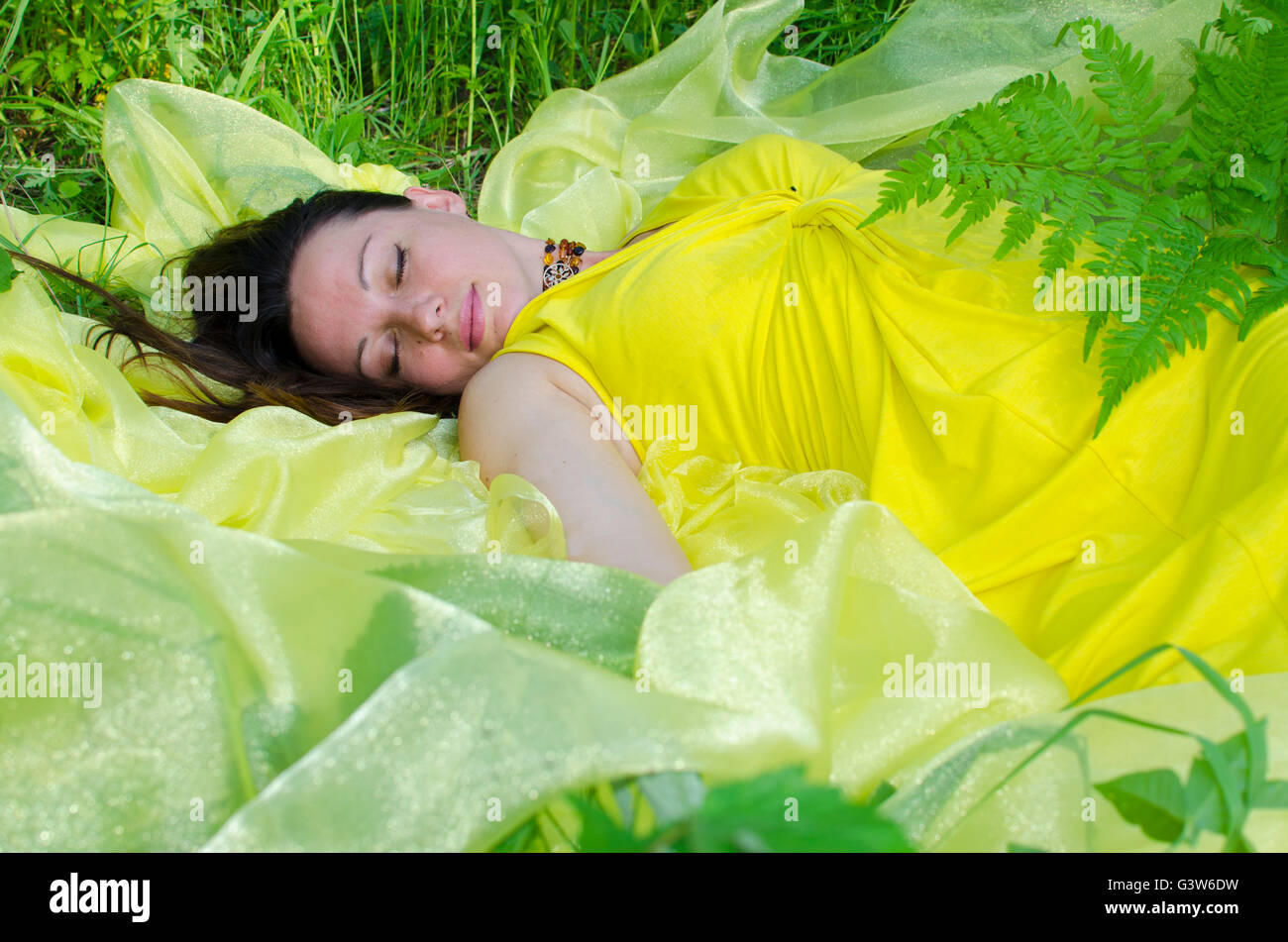 La giovane ragazza dorme sulla questione giallo in natura, giovane, la ragazza dorme, su giallo, materiale verde, un'erba, estate, la natu Foto Stock