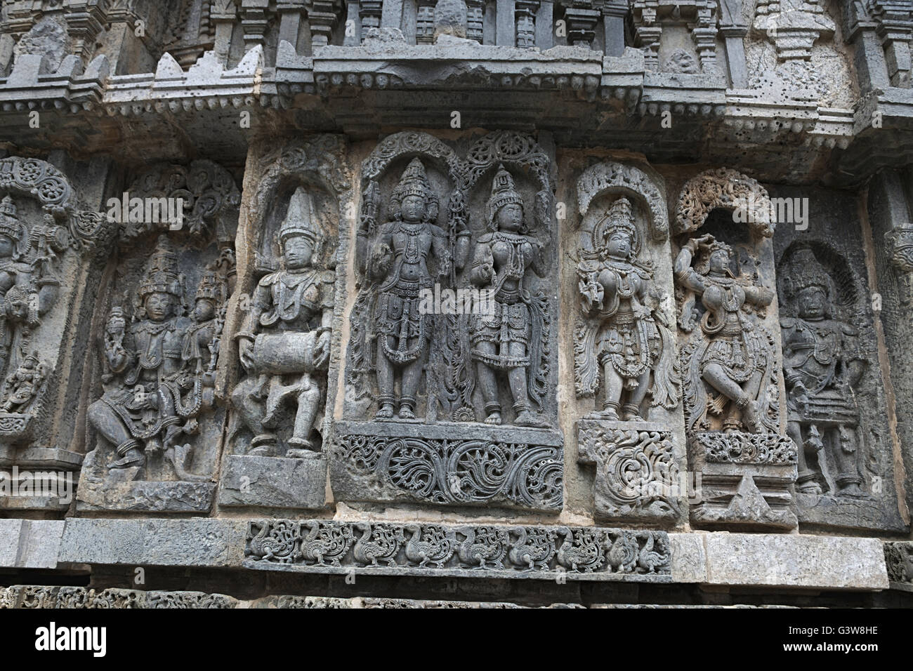 Ornati pannello parete bassorilievi raffiguranti (da sinistra) Shiva-Parvati, un drumer, Lakshmi-Narayana, tempio Kedareshwara, Halebid, India Foto Stock