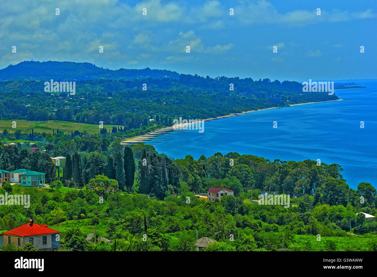 Panorama della costa del mare con piccola città balneare ed i contrafforti della dorsale montagnosa coperta da una fitta vegetazione Foto Stock