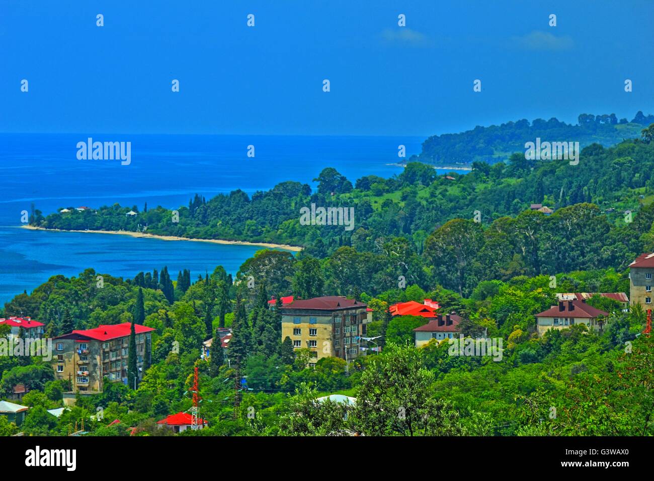 Panorama della costa del mare con piccola città balneare ed i contrafforti della dorsale montagnosa coperta da una fitta vegetazione Foto Stock