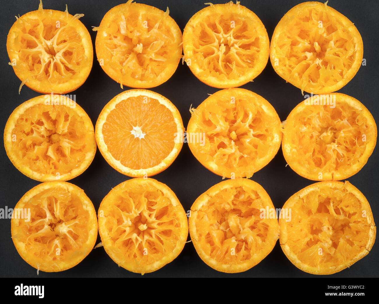 Spremuta di arance su uno sfondo nero, concetto, spicca tra gli altri, essere allegro e luminoso, pieno di energia Foto Stock