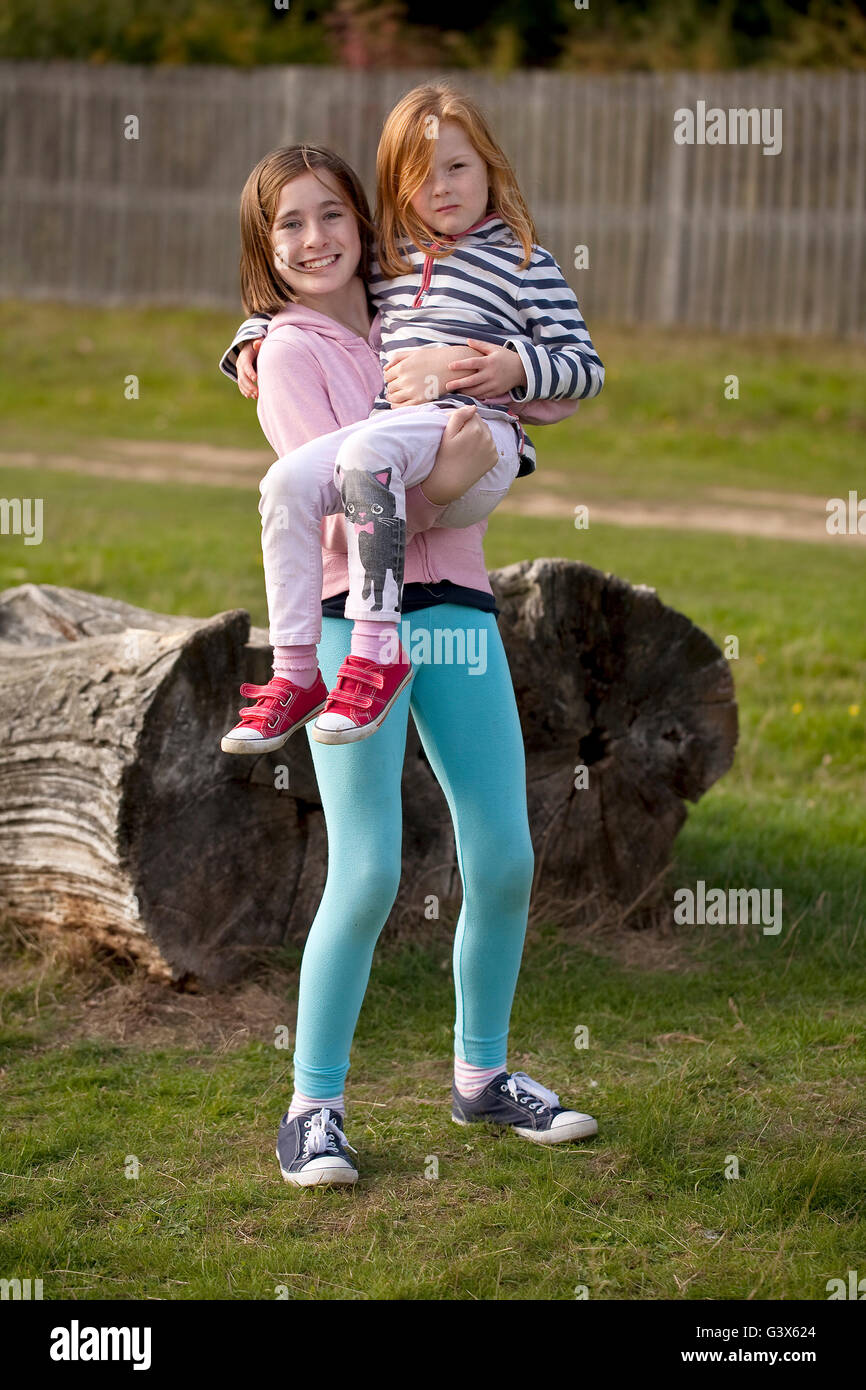 Sorelle. Una giovane ragazza è tenuto da sua sorella maggiore come giocano insieme nel parco. Foto Stock