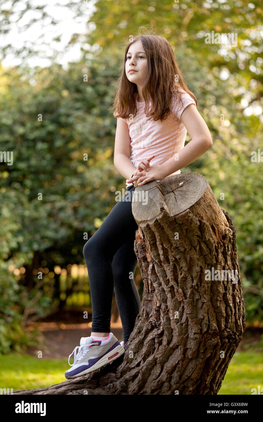 Nel profondo del pensiero. Una giovane ragazza ha scalato un albero ed è comodamente seduto a pensare a qualcosa. Foto Stock