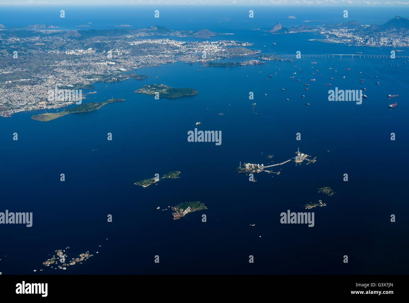 Vista aerea di intenso traffico marittimo nella baia di Guanabara, Rio de Janeiro, Brasile, dove petroliere e navi da carico, e le navi di supporto dominano le acque. La baia, un centro vitale per il trasporto marittimo e la logistica petrolifera, deve affrontare le sfide ambientali in corso a causa della proliferazione urbana, delle acque reflue non trattate, dei rifiuti solidi e delle perdite di petrolio ricorrenti, che minacciano tutti i suoi ecosistemi marini e la qualità delle acque. Foto Stock