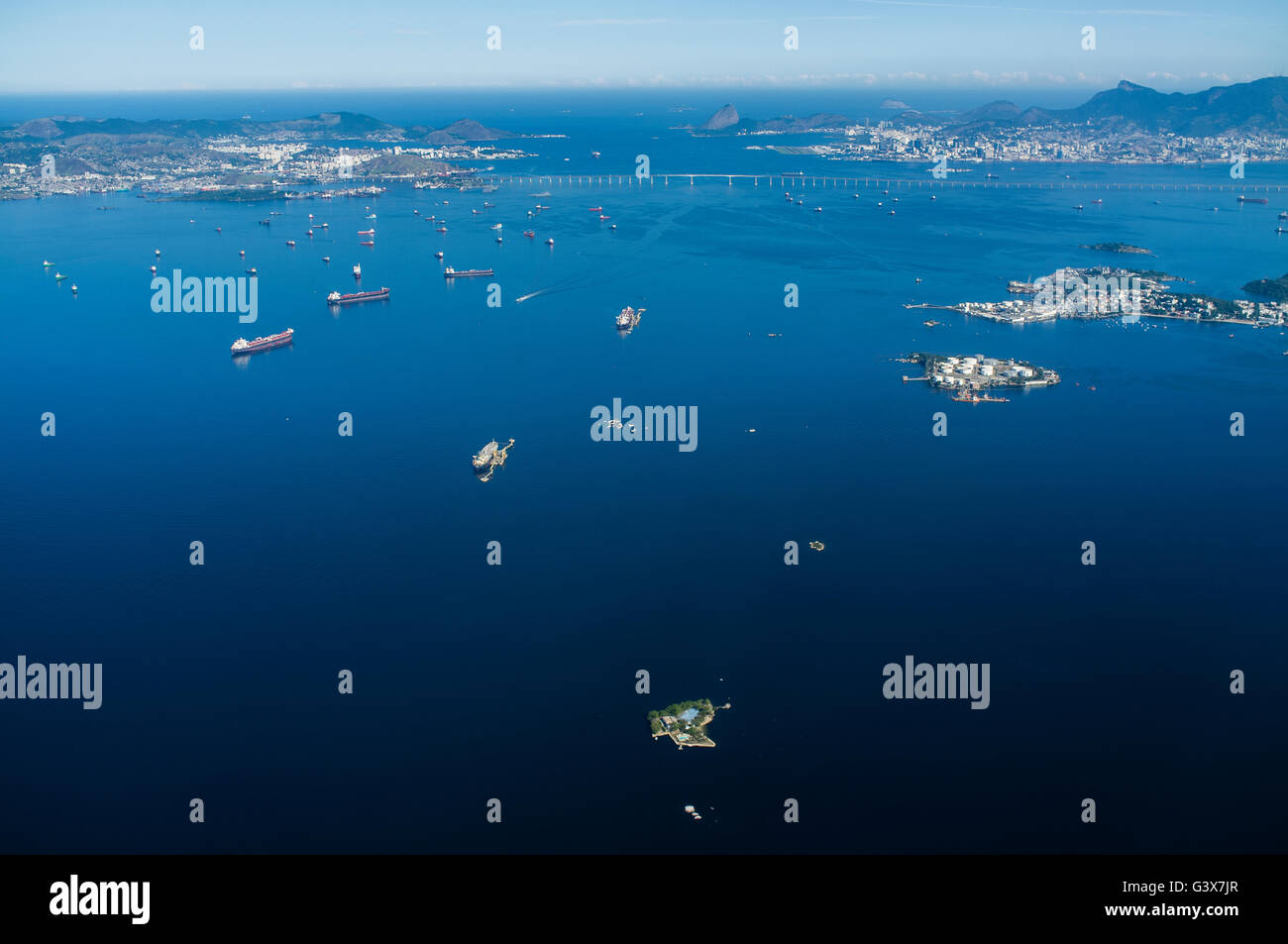 Vista aerea di intenso traffico marittimo nella baia di Guanabara, Rio de Janeiro, Brasile, dove petroliere e navi da carico, e le navi di supporto dominano le acque. La baia, un centro vitale per il trasporto marittimo e la logistica petrolifera, deve affrontare le sfide ambientali in corso a causa della proliferazione urbana, delle acque reflue non trattate, dei rifiuti solidi e delle perdite di petrolio ricorrenti, che minacciano tutti i suoi ecosistemi marini e la qualità delle acque. Foto Stock
