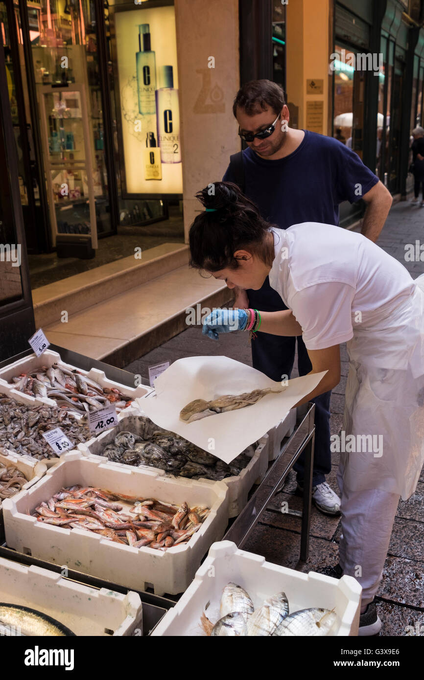 Pescivendolo calamari di incarto in carta per un cliente di un pesce in stallo sulla Via Draperie nel Quadrilatero distretto di Bologna, ho Foto Stock