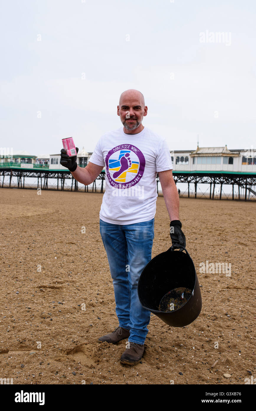 L'uomo aiutando a cancellare la lettiera e di altri rifiuti da una spiaggia di sabbia a Lytham St Anne's, lancashire, Regno Unito Foto Stock