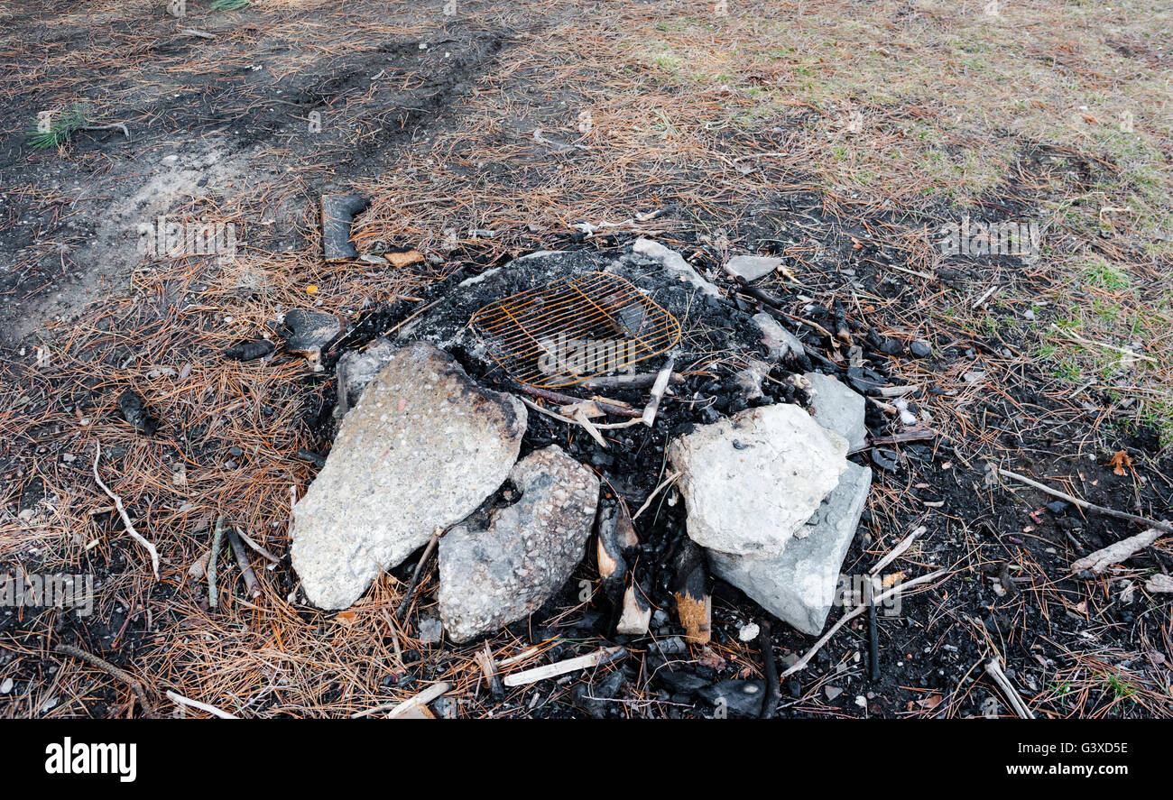 Utilizzate una buca per il fuoco e scorie e ceneri con pietre circostanti e la vecchia griglia in metallo a camp site. Foto Stock