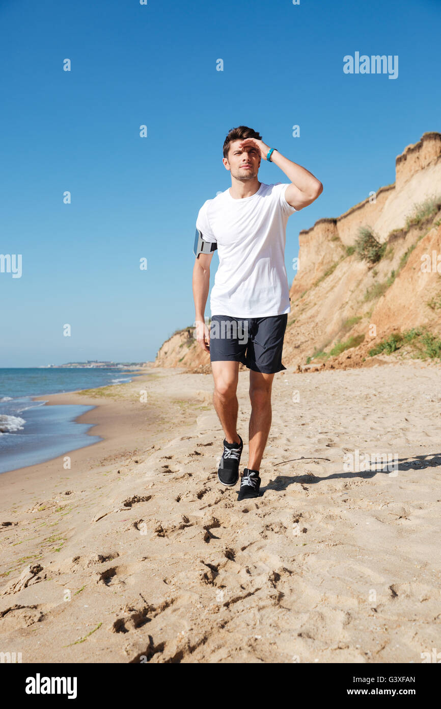 Attraente giovane atleta a piedi lungo la spiaggia Foto Stock