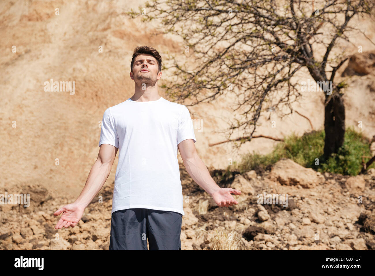 Rilassata bel giovane uomo in piedi e meditando all'aperto Foto Stock