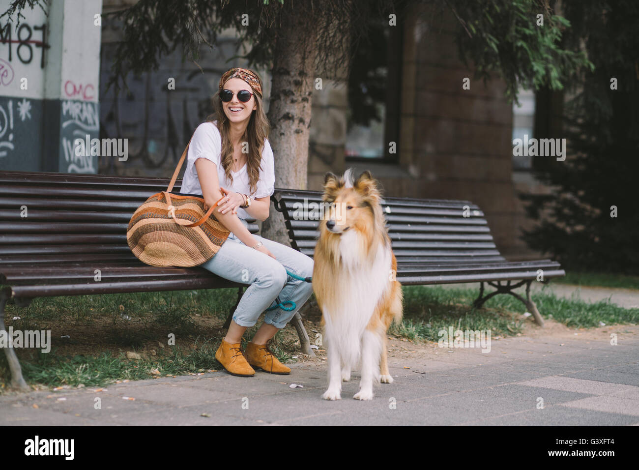 Giovane donna seduta sulla strada con il suo cane Foto Stock