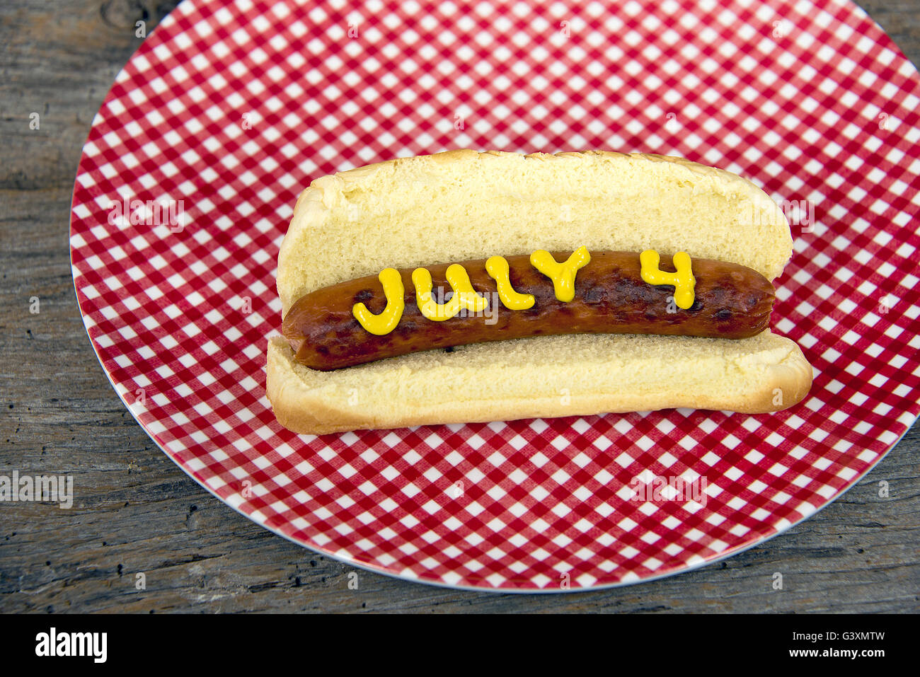 Hot Dog sul panino con mostarda in bianco e rosso Gingham piastra per quarto di luglio vacanza. Foto Stock