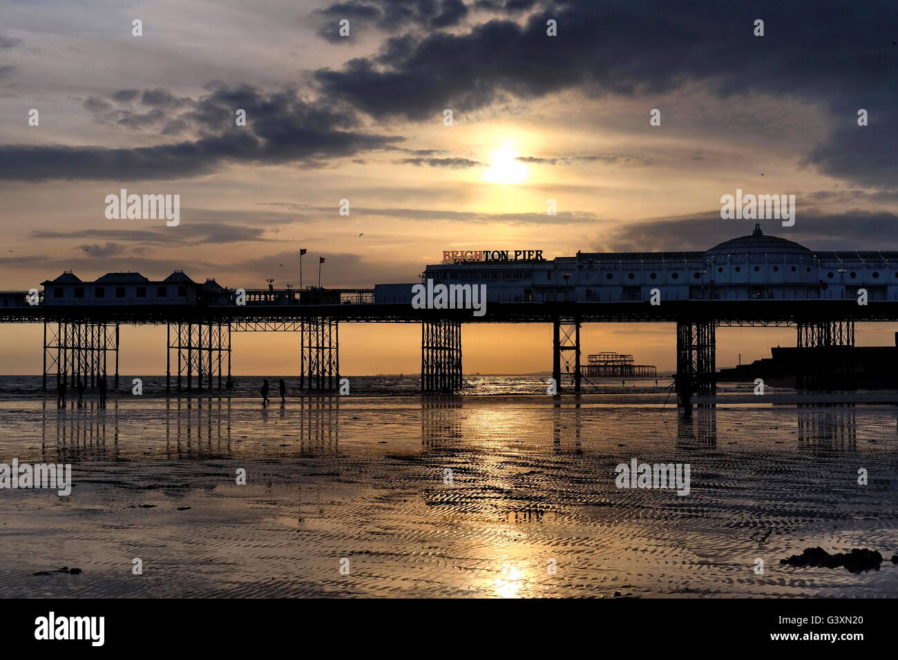 Un basso Sun in un tardo pomeriggio di primavera sagome due piloni in Brighton. Foto Stock