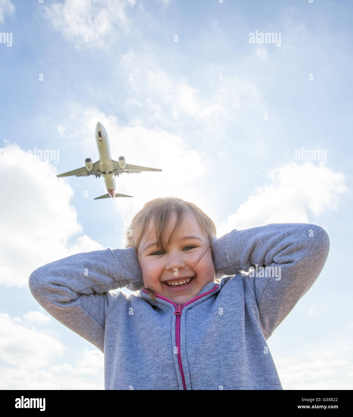 Un giovane bambino che copre le loro orecchie come un velivolo vola overhead vicino aeroporto Foto Stock
